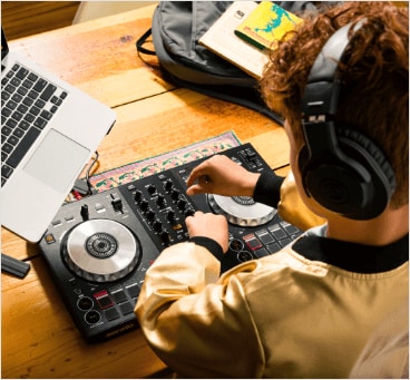 Boy with headphones learning how to DJ in class.