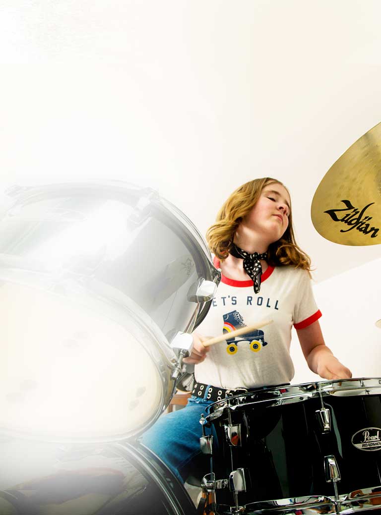 Girl playing drum set during drum lessons.