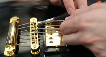 person aligning guitar strings