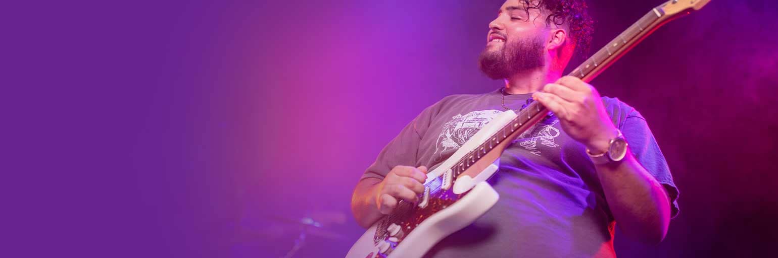 Man strumming electric guitar on stage.