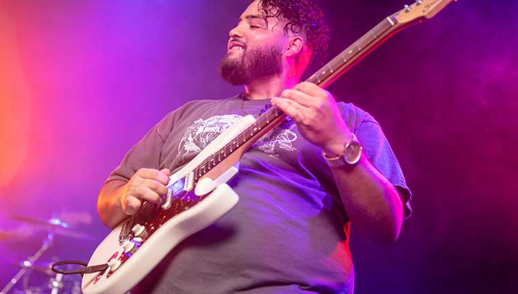 Man strumming electric guitar on stage.