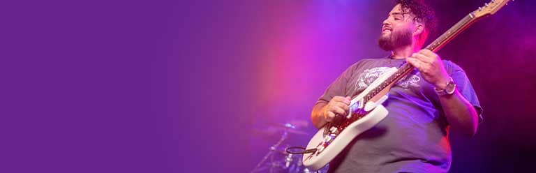 Man strumming electric guitar on stage.