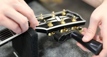 person adjusting guitar string tension